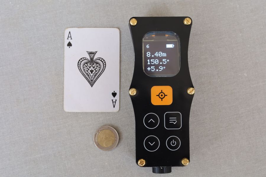 The DiscoX laid flat beside an ace of spades playing card and a coin, showing it is a little longer and slightly wider than the card.