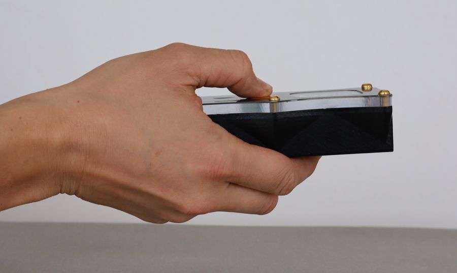 The DiscoX gripped in a closed fist seen from behind, the body sitting across the palm.